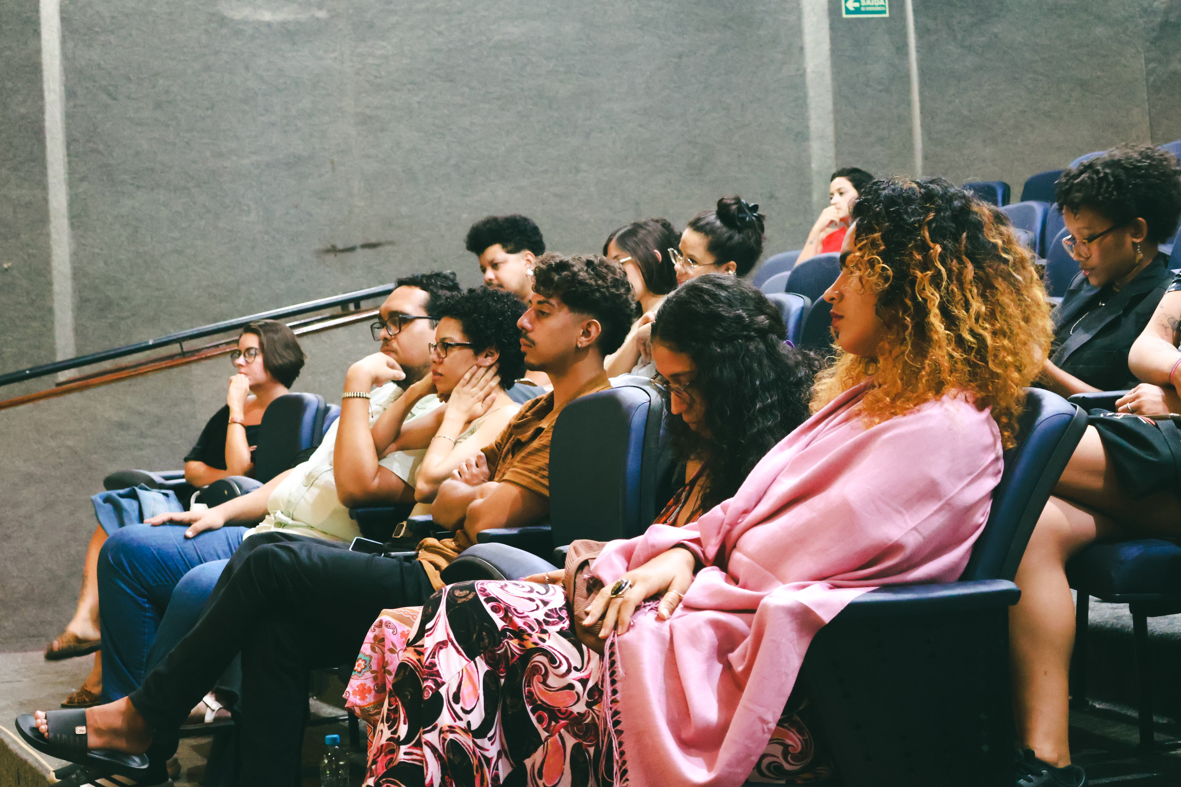 Fotografia. Mão segurando uma fotografia antiga em preto e branco, com foco no gesto e na imagem parcialmente desfocada.