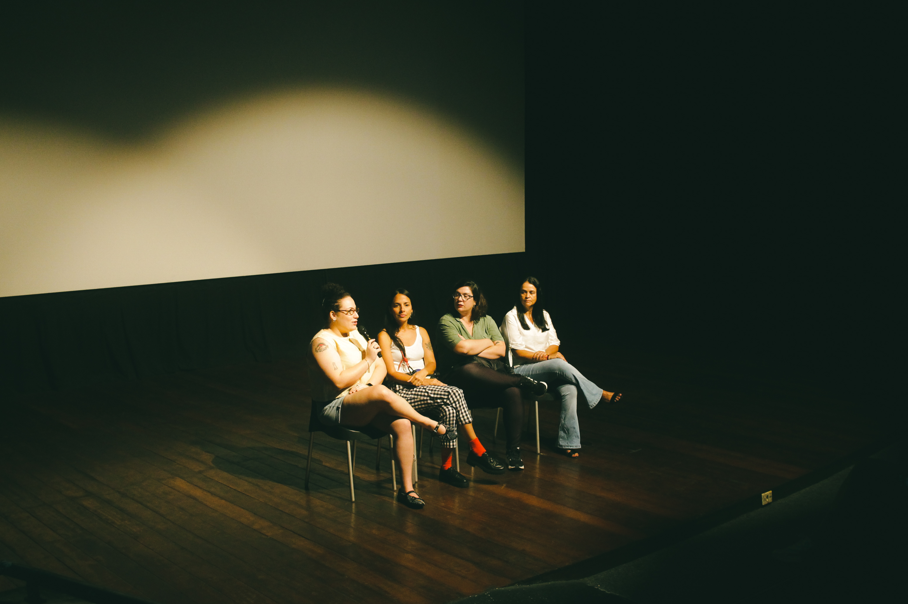 Fotografia. Mão segurando uma fotografia antiga em preto e branco, com foco no gesto e na imagem parcialmente desfocada.