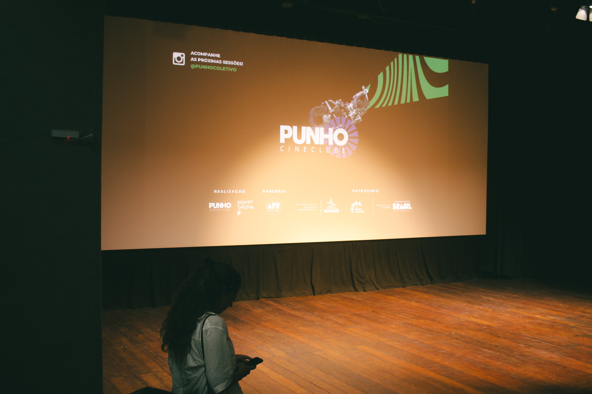 Fotografia. Close em tecido laranja com textura acetinada. O tecido está amassado, formando curvas e sombras suaves.